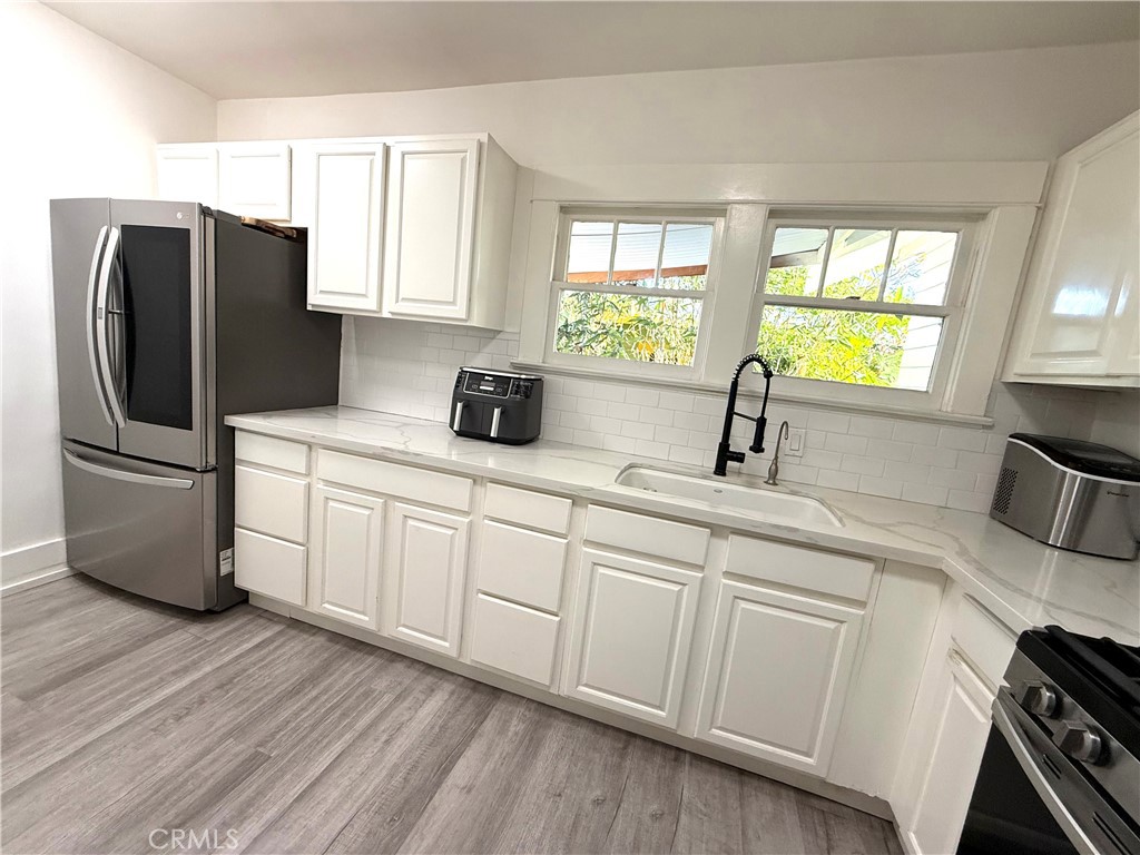 6226 Washington Whittier, CA 90601 - Photo 5 of 21 a kitchen with stainless steel appliances white cabinets a sink a window and a refrigerator