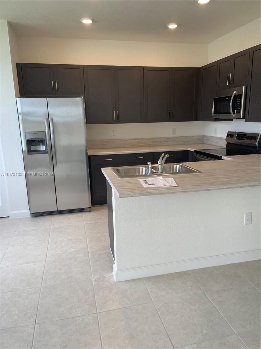 20564 Northeast 5th Place Miami, FL 33179 - Photo 17 of 38 a kitchen with a sink a refrigerator and cabinets