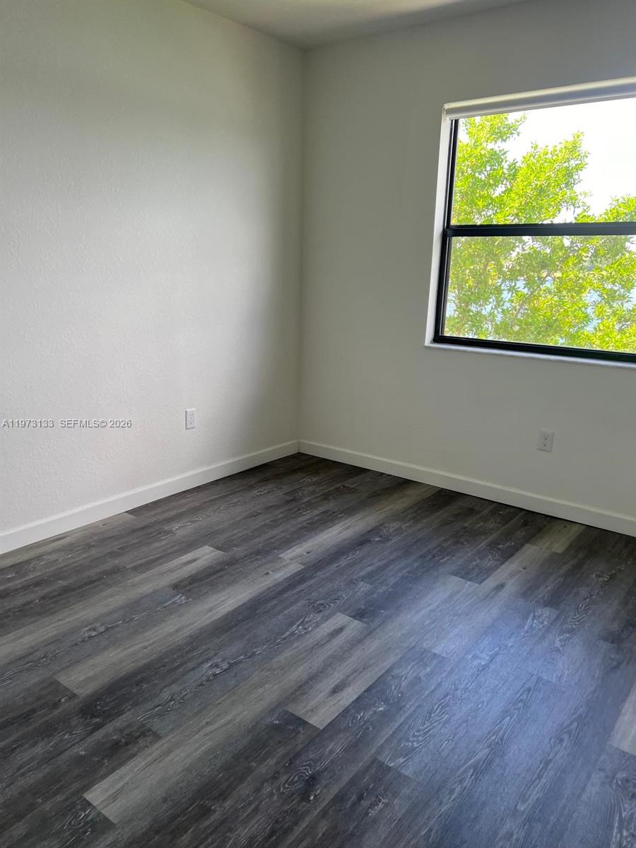 20564 Northeast 5th Place Miami, FL 33179 - Photo 18 of 38 a view of an empty room with wooden floor and a window