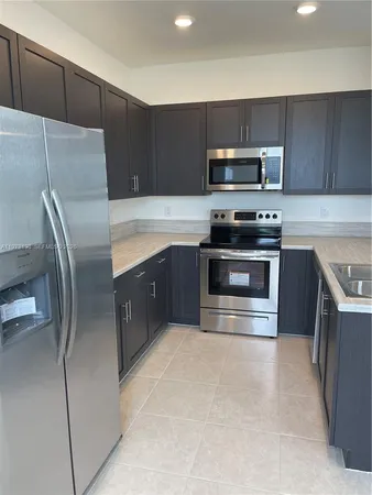 a kitchen with stainless steel appliances granite countertop a stove a microwave a sink and a refrigerator