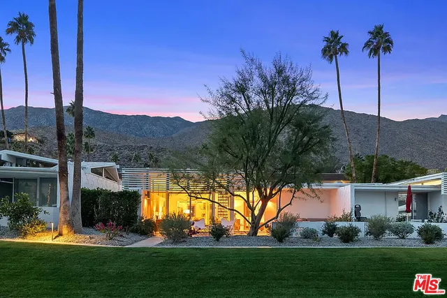 a view of a house with a big yard and palm trees