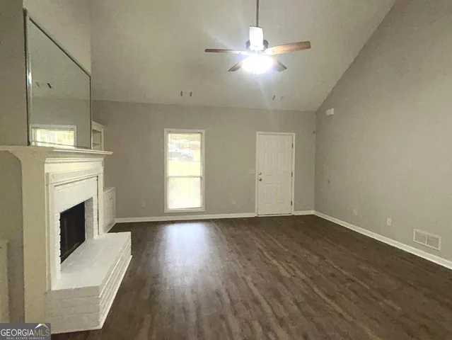 an empty room with wooden floor fireplace and windows