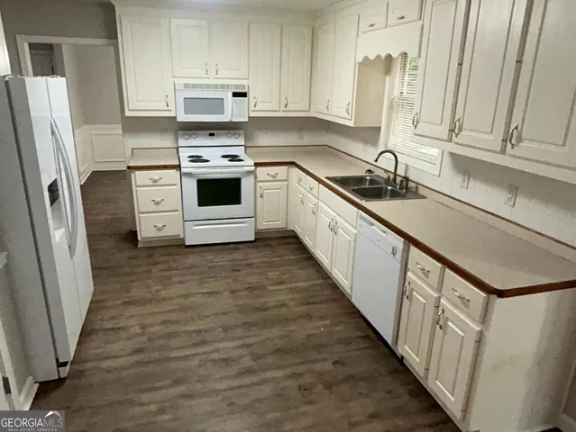 a kitchen with stainless steel appliances a refrigerator a sink a stove and white cabinets