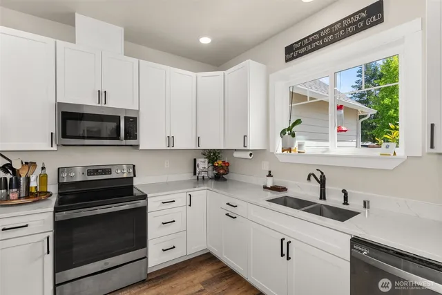 a kitchen with cabinets appliances a sink and a window
