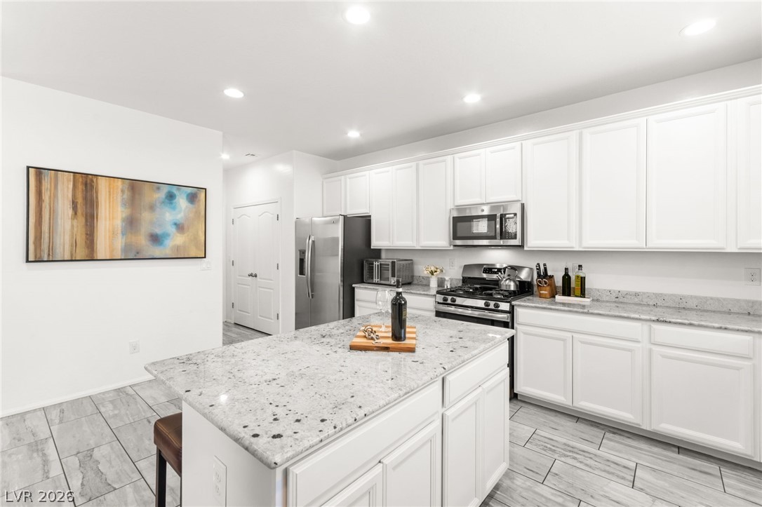 6435 Point Isabel Way Las Vegas, NV 89122 - Photo 15 of 57 Culinary dreams come alive in this well-lit kitchen, featuring abundant white cabinetry and speckle-patterned countertops.