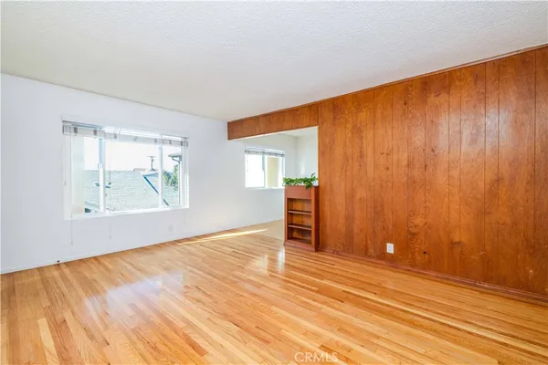 an empty room with wooden floor and windows with curtains