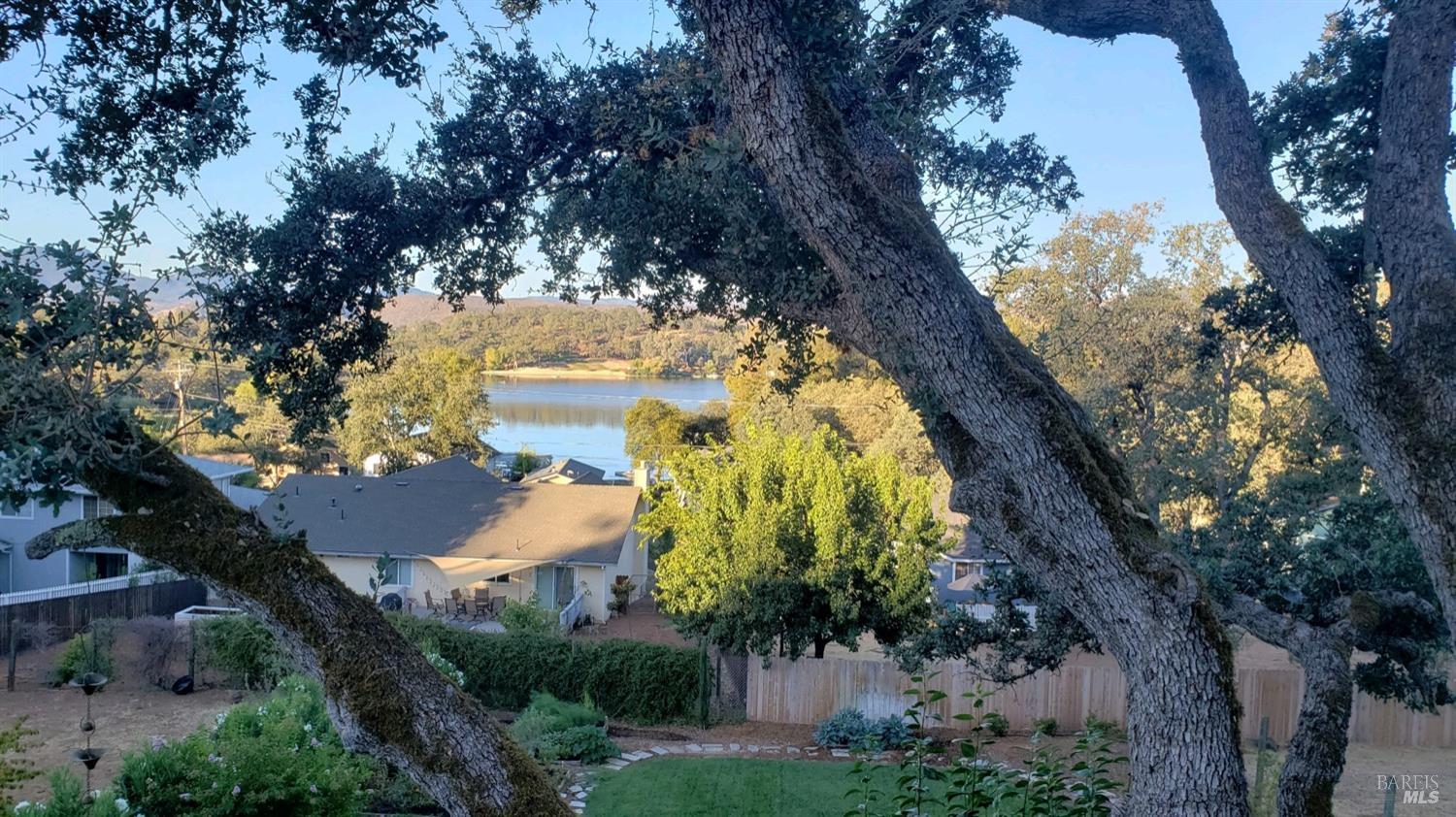 18903 Deer Hill Road Hidden Valley Lake, CA 95467 - Photo 23 of 32 Lake views through magnificent oaks from the neighboring lot of similar size and topography to the vacant lot for sale. The owners have built decks off the back of the home to take in even greater views from nearly the entire backside of their home.