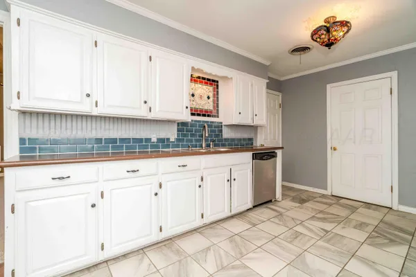 a kitchen with white cabinets and sink