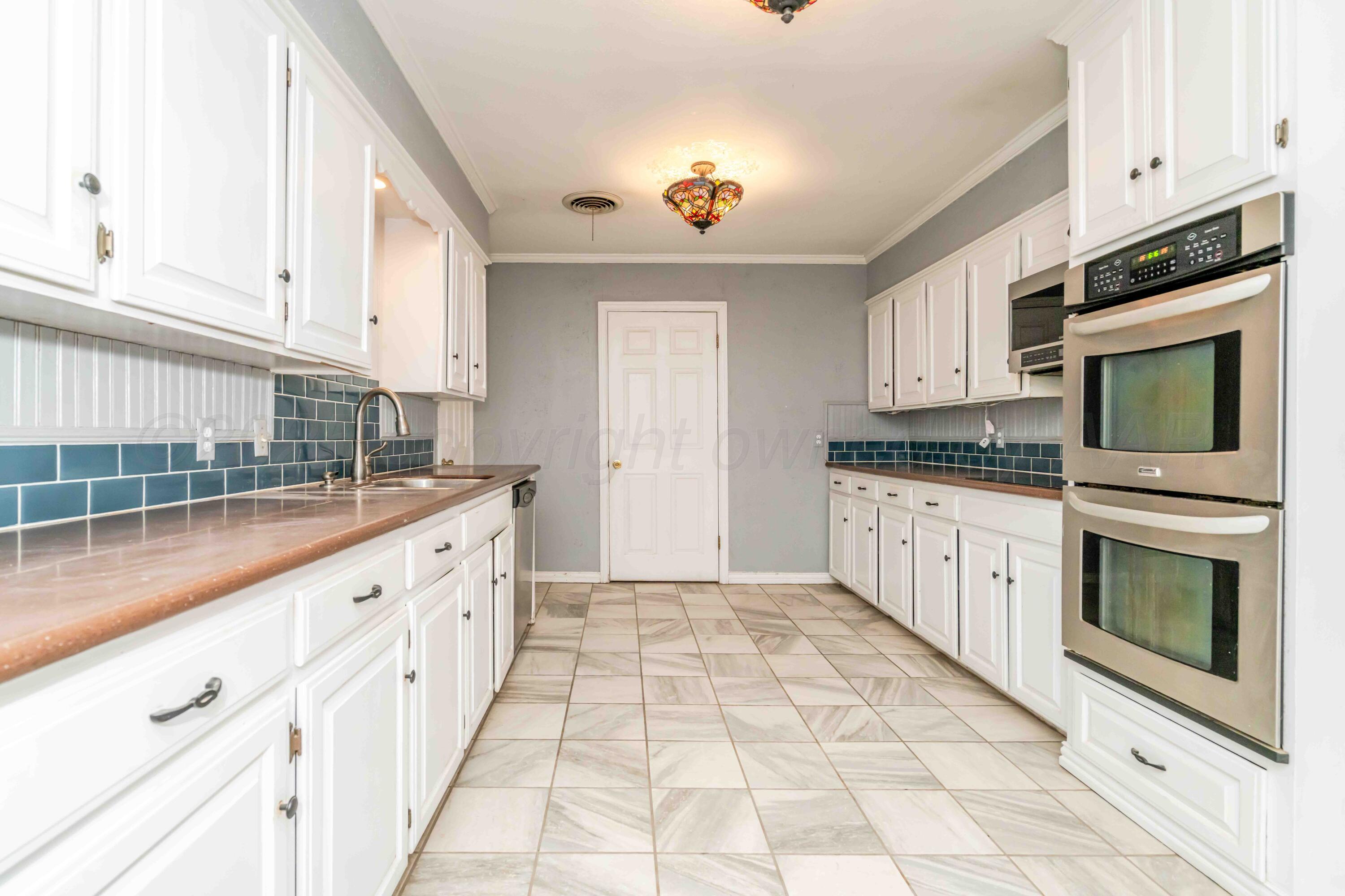 39 Crockett Drive Tulia, TX 79088 - Photo 12 of 29 a kitchen with granite countertop a stove top oven microwave and cabinets