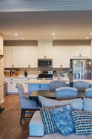 a living room with couches and kitchen view with wooden floor