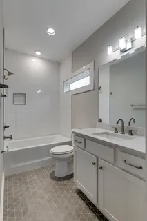 a bathroom with a toilet a sink a tub and a mirror