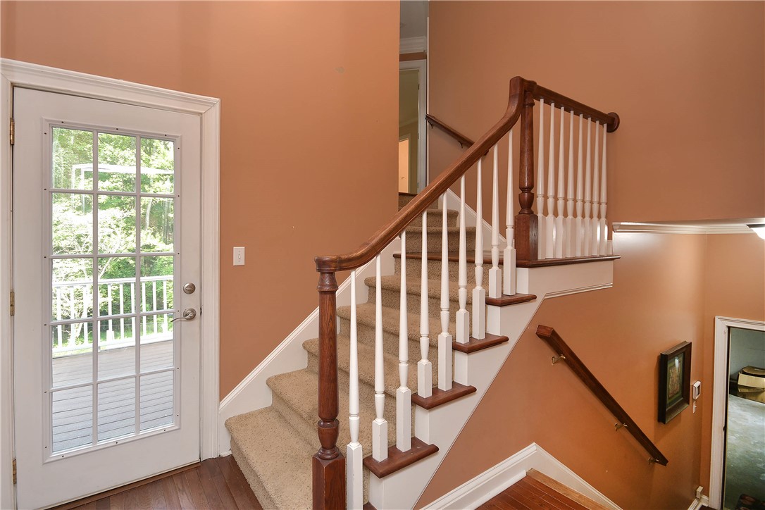 197 Deer Creek Road Easley, SC 29640 - Photo 18 of 50 A grand wooden staircase with carpeted steps elegantly ascends towards the upper level, offering a welcoming entryway.