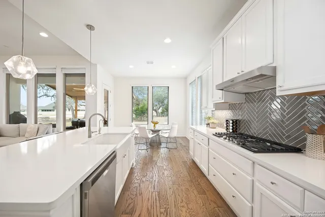 a large kitchen with kitchen island a large window a sink stainless steel appliances and cabinets