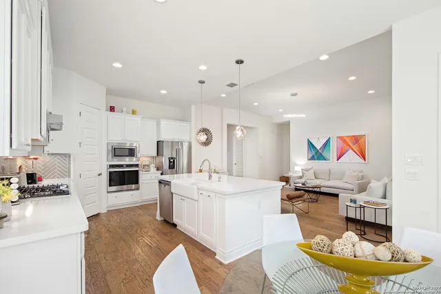a living room with stainless steel appliances furniture and a kitchen view