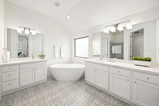 a spacious bathroom with a double vanity sink mirror and bathtub