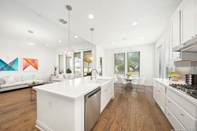a large white kitchen with a large window a sink and appliances