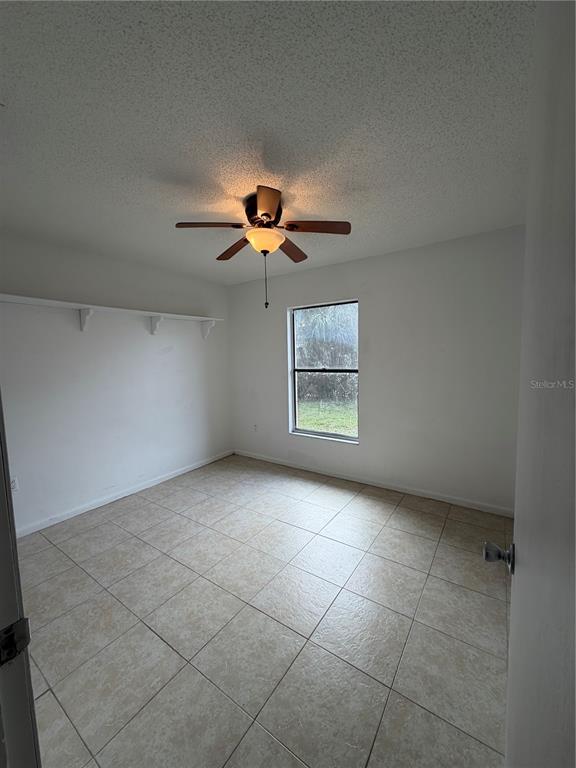 6820 Northeast 7th Street, Unit B Ocala, FL 34470 - Photo 8 of 11 an empty room with chandelier fan and windows