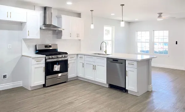 a kitchen with stainless steel appliances a stove a sink and wooden floors