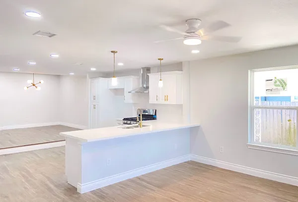 a large kitchen with stainless steel appliances a large counter top a sink a refrigerator and a window