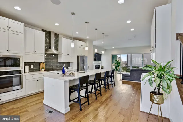 a room with stainless steel appliances kitchen island granite countertop furniture wooden floor and a view of living room