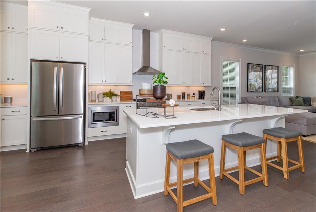 a kitchen with stainless steel appliances granite countertop a table chairs sink refrigerator and microwave