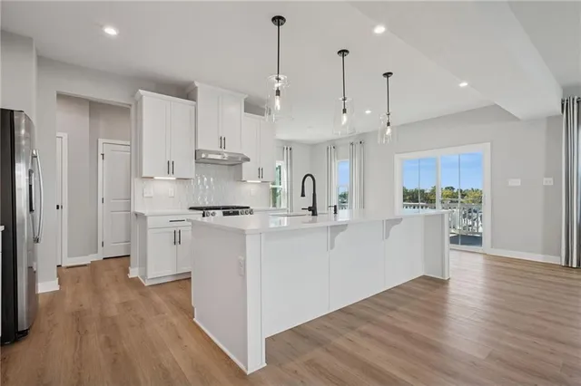 a kitchen with stainless steel appliances sink refrigerator and wooden floor