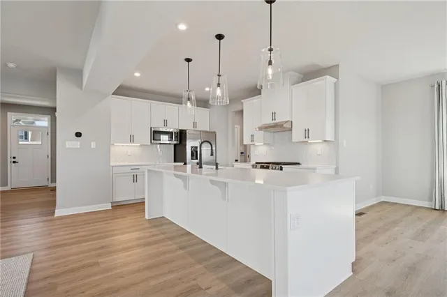 a large white kitchen with lots of counter space sink and appliances