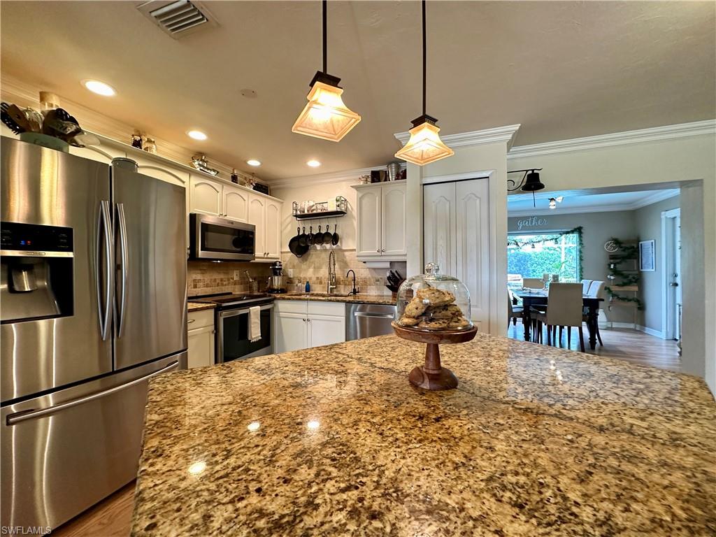 17444 Ingram Road Fort Myers, FL 33967 - Photo 3 of 27 Kitchen with white cabinetry, tasteful backsplash, hardwood / wood-style floors, appliances with stainless steel finishes, and pendant lighting