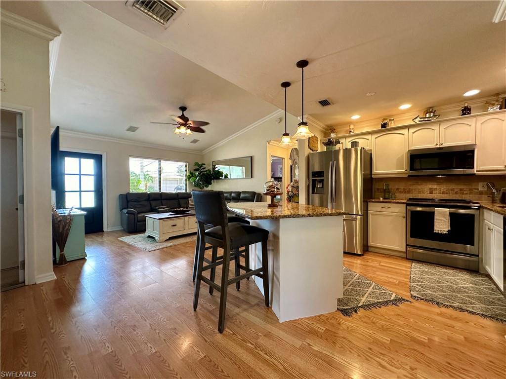 17444 Ingram Road Fort Myers, FL 33967 - Photo 5 of 27 Kitchen with appliances with stainless steel finishes, light wood-type flooring, lofted ceiling, ceiling fan, and ornamental molding