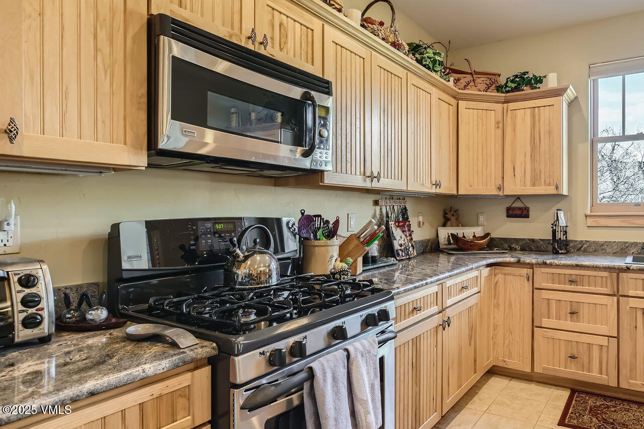 1987 Eagle Ranch Road Eagle, CO 81631 - Photo 14 of 37 a kitchen with granite countertop a stove top oven microwave and cabinets