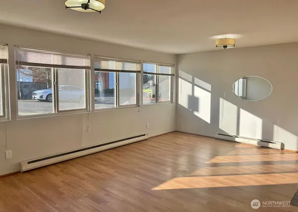 a view of an empty room with wooden floor and a window