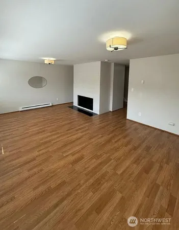 a view of an empty room with wooden floor and window