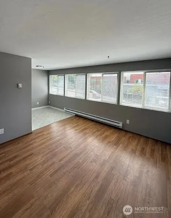 an empty room with wooden floor and windows