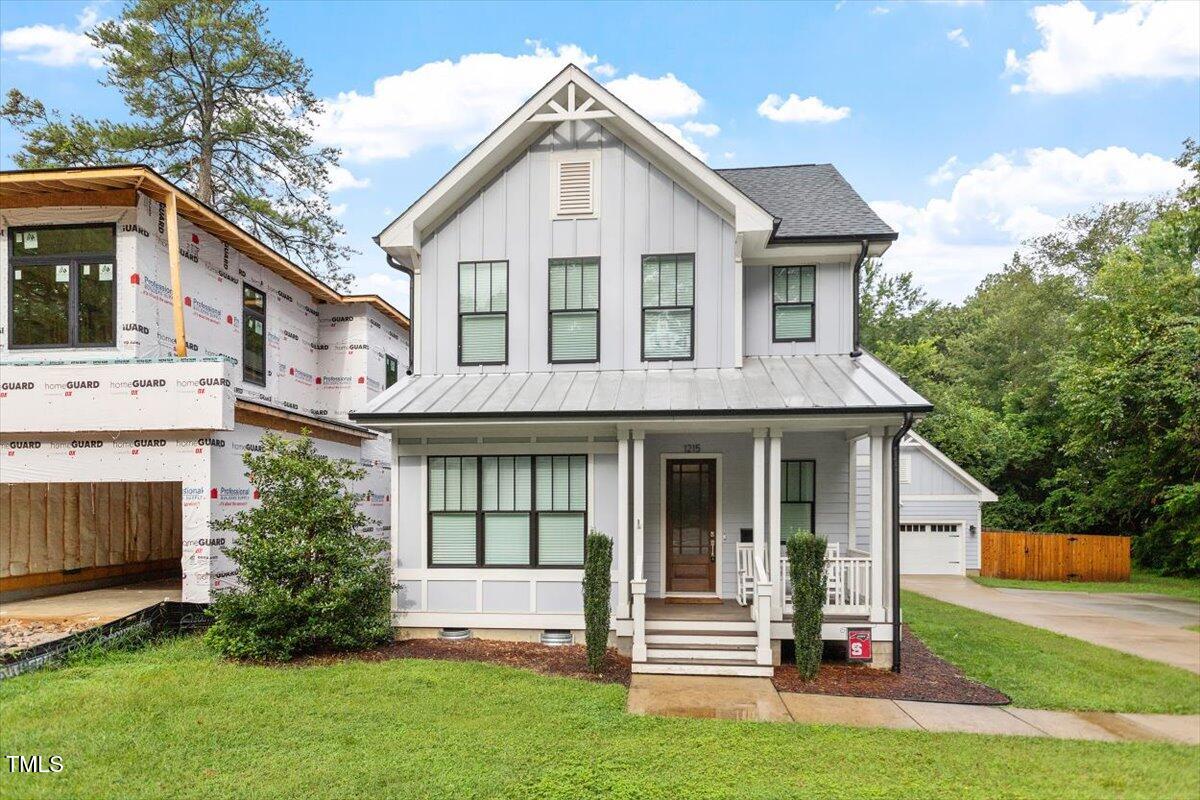 1215 Brookside Drive Raleigh, NC 27604 - Photo 1 of 34 a view of a white house with large windows and a yard with plants and large trees