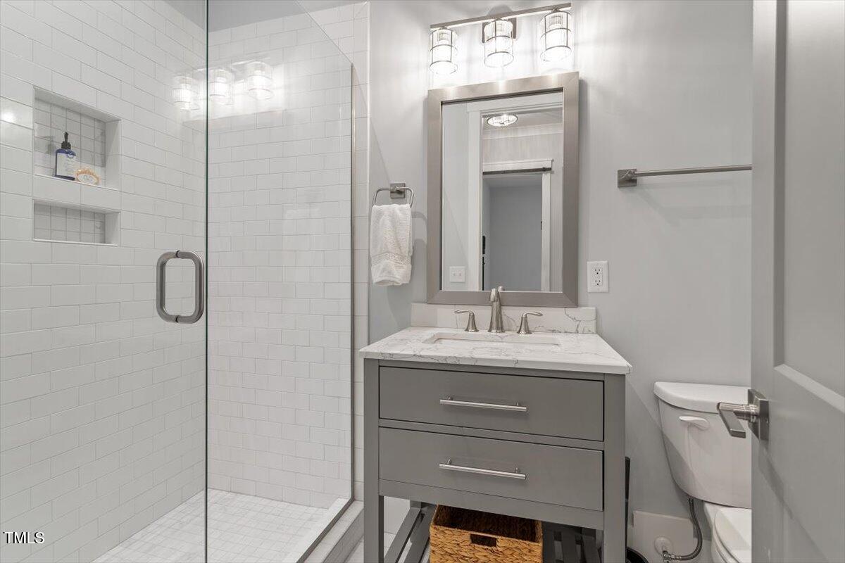 1215 Brookside Drive Raleigh, NC 27604 - Photo 17 of 34 a bathroom with a granite countertop sink a toilet a mirror and shower