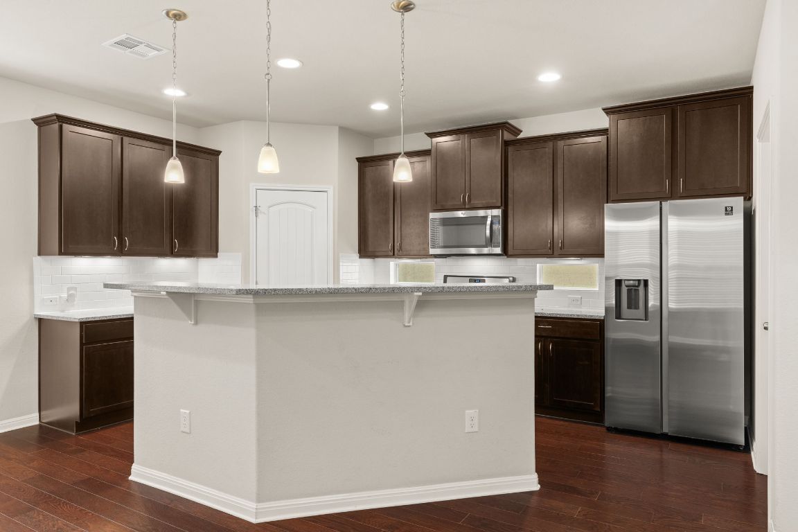 7709 Menchaca Road, Unit 5 Austin, TX 78745 - Photo 6 of 21 a modern kitchen with stainless steel appliances kitchen island granite countertop a refrigerator a sink a stove and a microwave