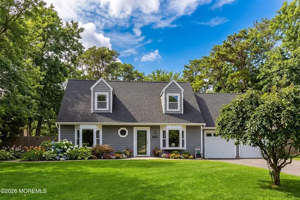 a front view of a house with a garden and trees