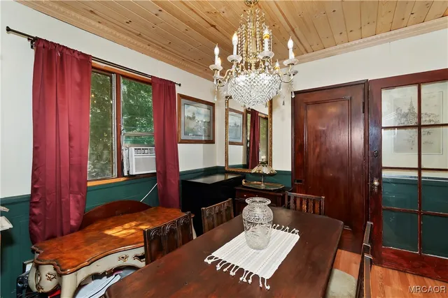 a view of a dining room with furniture a chandelier and large window