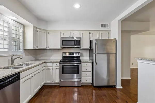 a kitchen with a refrigerator sink and wooden floor
