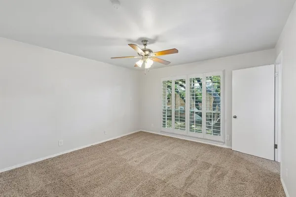 an empty room with windows and ceiling fan