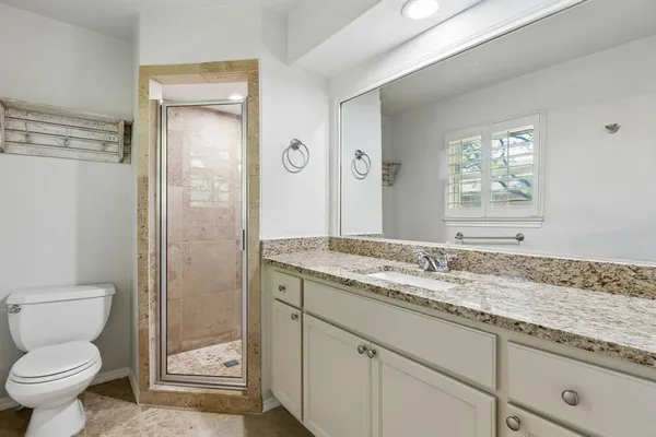 a bathroom with a granite countertop sink toilet and shower
