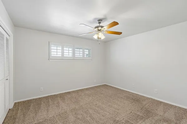 an empty room with a window and ceiling fan