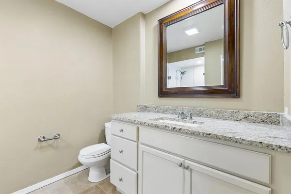 a bathroom with a granite countertop toilet sink and mirror