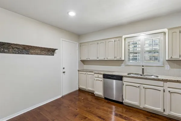 a kitchen with stainless steel appliances granite countertop a sink and a stove with wooden floors