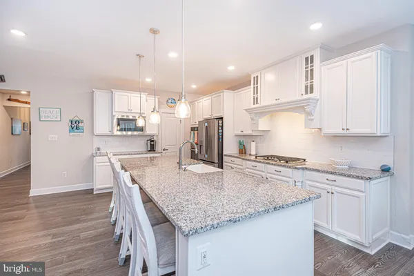 a dining room with stainless steel appliances kitchen island granite countertop a dining table chairs and a living room view