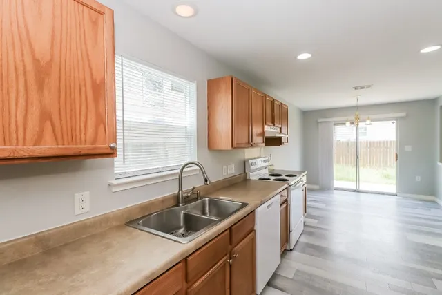 a kitchen with stainless steel appliances granite countertop a stove top oven a sink dishwasher and a refrigerator with wooden cabinets