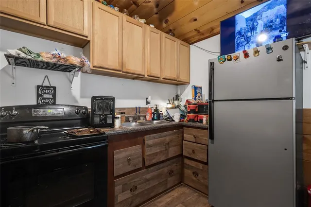 a kitchen with granite countertop a refrigerator and a stove top oven