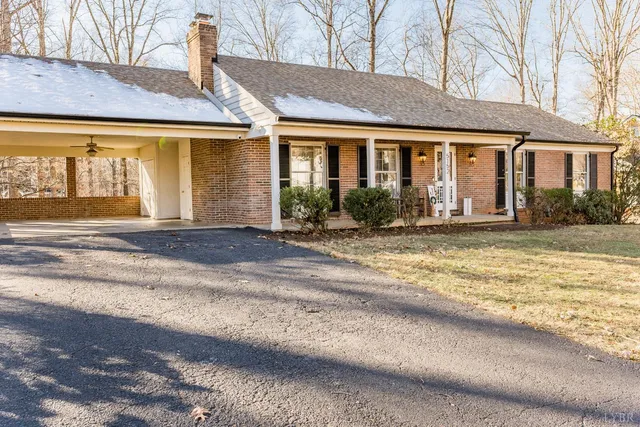 a view of a house with a large window and a yard with table and chairs under an umbrella