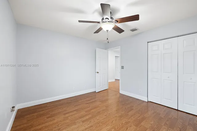 an empty room with wooden floor fan and windows