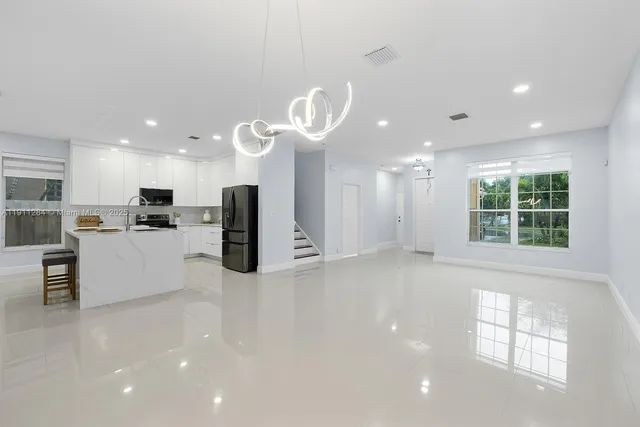 a view of a kitchen with kitchen island stainless steel appliances a window and a counter top space